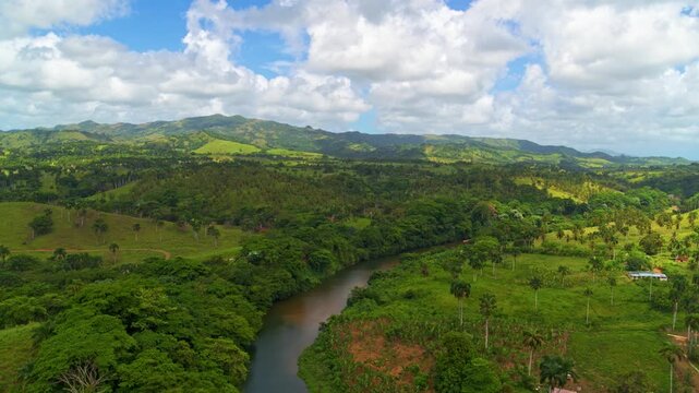 A river meanders through lush, green waterways with trees and a cloudy sky. Landscape with a stream flowing through a mountain valley. Mountainous landscape of Central America, aerial view.