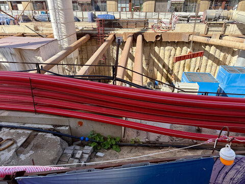 Inside look at subway station construction pit with heavy steel shoring struts and equipment