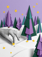 Naklejka premium Paper cut winter landscape with purple trees green forest yellow stars and a grayscale hand reaching through snow