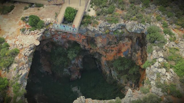 View of Cehennem, the Hell Sinkhole, part of the famous Cennet ve Cehennem natural landmarks near Silifke in Mersin Province, Turkiye. Deep rocky chasm surrounded by Mediterranean vegetation.