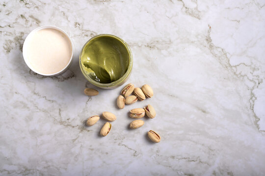 jar of creamy pistachio butter with whole nuts on marble surface, gourmet food concept, copy space
