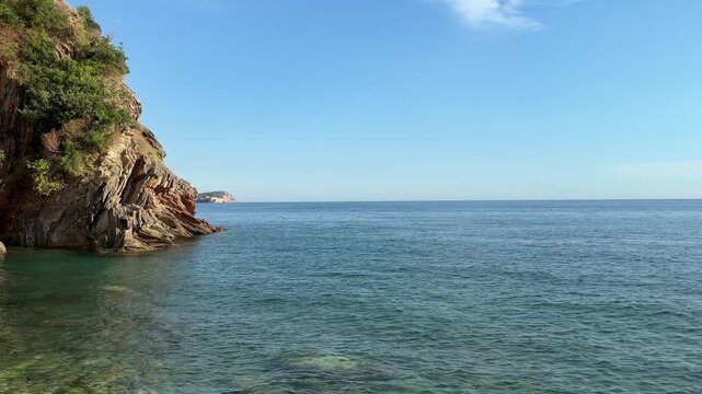 Crystal clear blue sea water along a rugged rocky coastline, pristine  landscape on a sunny summer day