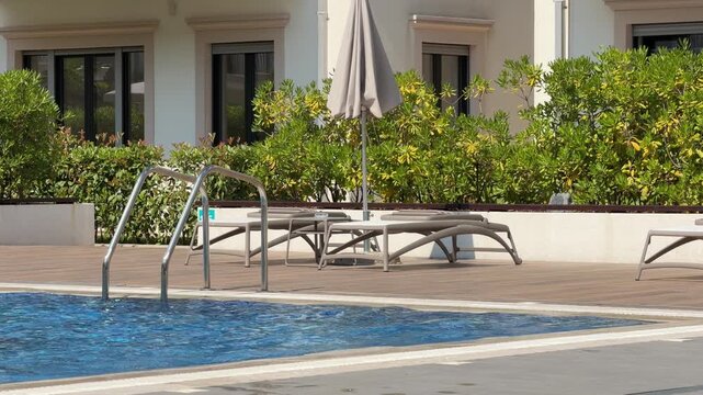 Hotel sun loungers by the swimming pool on a sunny summer day, relaxing resort atmosphere and luxury vacation concept