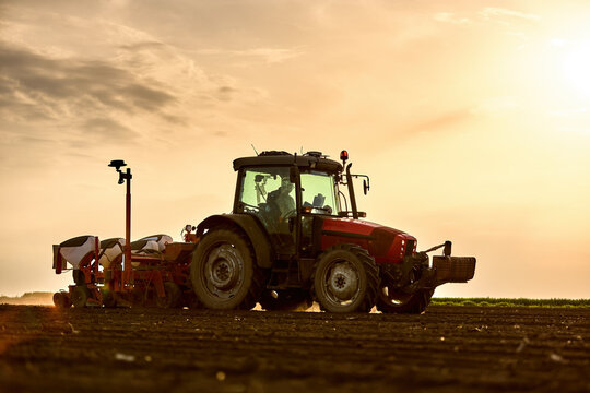 Farmer seeding field with tractor at sunset, modern agriculture and future farming