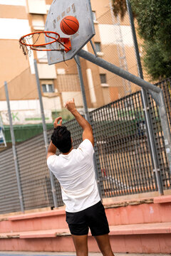 Man shooting basketball on an outdoor court, enjoying urban sport