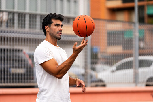 Man balancing spinning basketball on finger showing concentration and urban sport skill