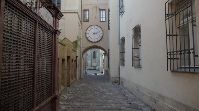 Historic Passage with Large Clock in Lviv Old Town Narrow cobblestone passage leading beneath an arch with a large historic clock in the old town of Lviv, Ukraine.