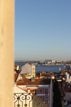 view of Lisbon, Portugal from a private balcony looking over rooftops towards Tagus River during late afternoon