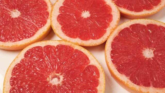 Fresh juicy grapefruit slices rotating on a white background