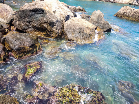 Clear blue ocean water flowing over rocky coastal shoreline and tide pools
