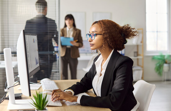 Businesswoman accountant in office analyzing spreadsheet report. Focused professional uses computer to review financial data and prepare budgets. Workplace concept of finance and analysis.