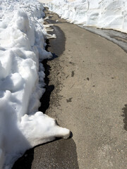 Fototapeta premium Snow-lined path with wet asphalt