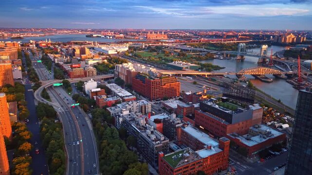 Footage over the beautiful waterfront of the Harlem River at sunset. Flight over the highways along the rows of green trees. New York City, USA.