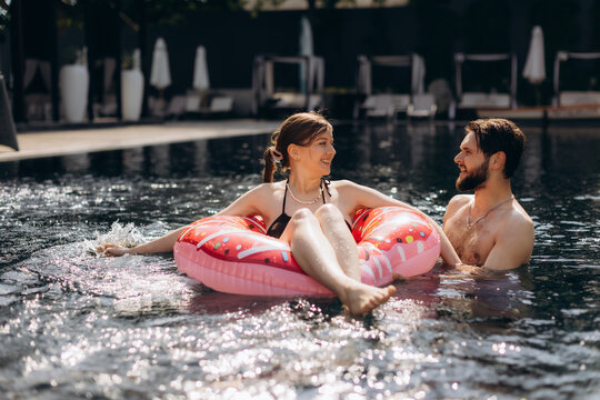 Couple relaxing in swimming pool with donut float