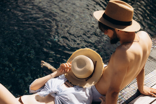 Couple relaxing by swimming pool enjoying summer vacation