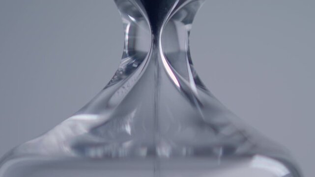 Close up macro shot of sand clock / hourglass sand pouring in slow motion.