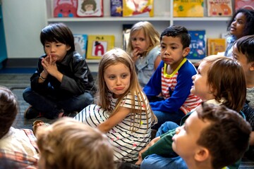 Fototapeta premium Children sitting on the floor in a classroom, listening attentively.