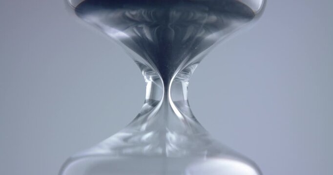Close up macro shot of sand clock / hourglass sand pouring in slow motion.