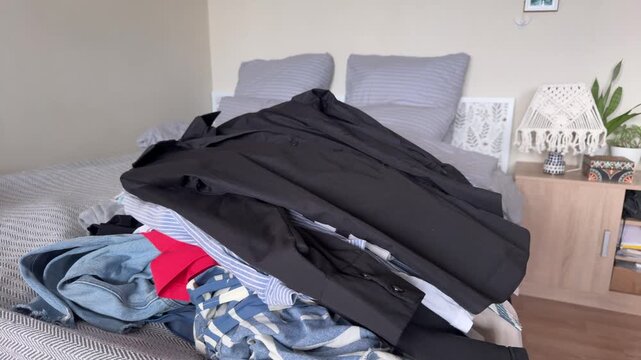 Person throwing clothes with hangers onto bed, home organization and decluttering concept, wardrobe sorting, vertical video