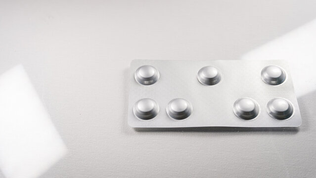 Close up of a silver blister pack with tablets isolated on a clean white background. Pharmaceutical medicine packaging and healthcare medication concept