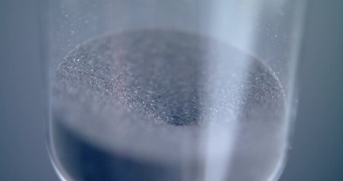 Close up macro shot of sand clock / hourglass sand pouring in slow motion.