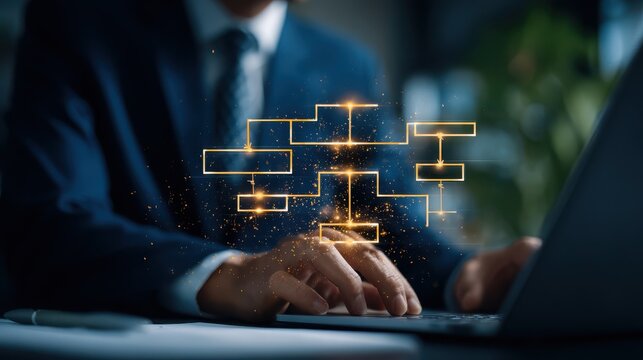 A businessman typing on a laptop with a glowing digital flowchart graphic hovering above. This corporate technology image illustrates workflow management systems.