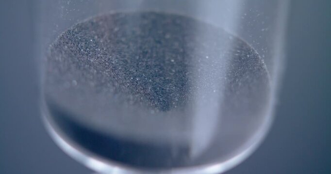 Close up macro shot of sand clock / hourglass sand pouring in slow motion.