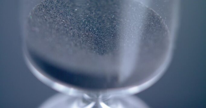 Close up macro shot of sand clock / hourglass sand pouring in slow motion.