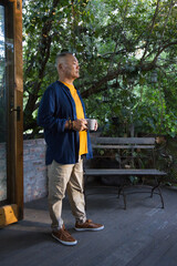 Senior Asian man standing on wooden deck at home, holding white mug near midsection © WavebreakMediaMicro