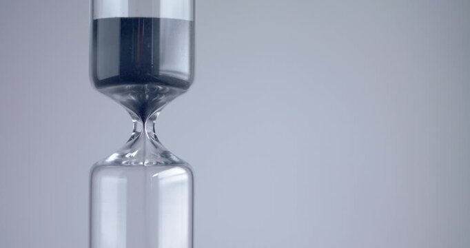 Close up shot of modern design sand clock / hourglass on a grey background.