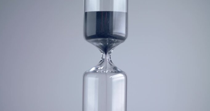 Close up shot of modern design sand clock / hourglass on a grey background.