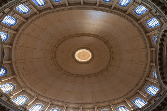 Grand symmetrical dome interior showcasing a central skylight, surrounding arched windows and classical columns in a historic rotunda. Basilica of Our Lady of Mount Carmel, Valletta, Malta