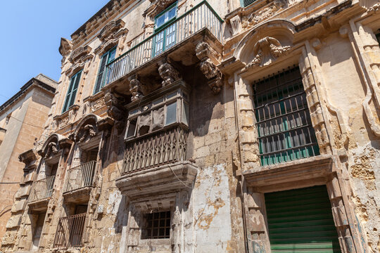 Traditional Maltese wooden balconies and shuttered windows, architectural detail and Mediterranean charm under clear blue sky. Valletta old town street view