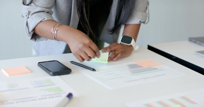 Woman's hands are picking up sticky pad, peeling notes and aligning them to label charts