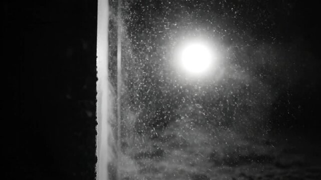 Black and white view of water flowing past a bright light in a dark environment creating a beautiful effect