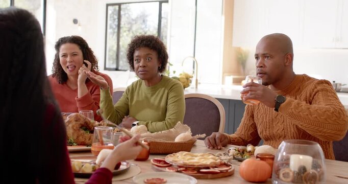 African American family listening to speaker at home table with turkey, woman exclaiming after news