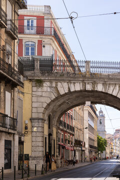 vertical shot of downtown street in Lisbon Portugal with historic bridge arch and storefronts