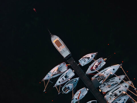 Premium top-down aerial view of modern sailboats moored at a marina dock