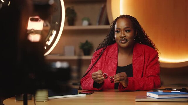 African American financial coach records video blog on phone in library