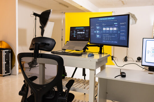 Workstation setup is occupying center of studio and is showing laptop on riser and dual monitors