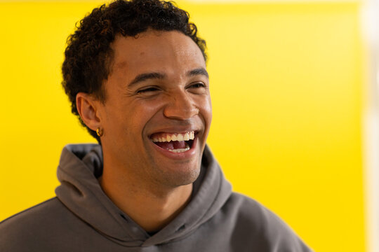 African American man laughing while wearing gray hoodie and showing gold hoop earring in studio