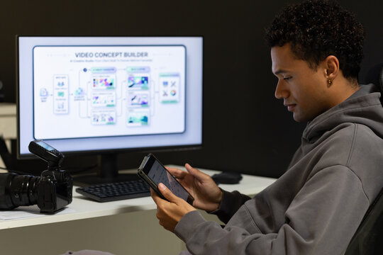 African American man hooded sitting at desk using tablet with chart on screen, camera, copy space