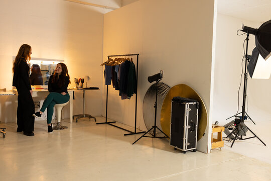 African American women preparing for shoot at vanity mirror with makeup and reflectors, copy space