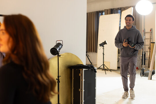 Male photographer and female model posing in studio while photographer holding DSLR and smiling
