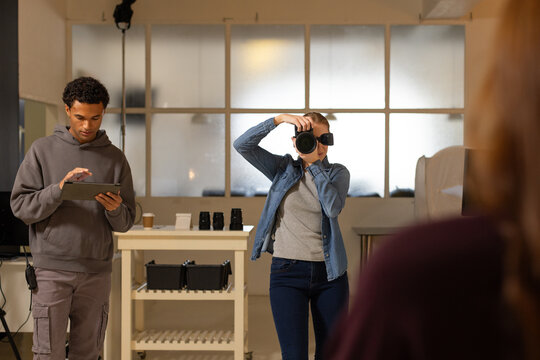 Diverse team shooting portrait in studio photographer in denim holding DSLR assistant using tablet