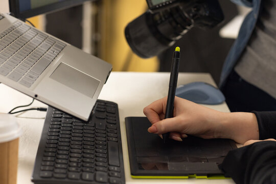 Diverse team working in studio using stylus on tablet, photographer in denim jacket holding DSLR