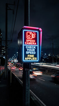 Bright Neon Speed Camera Sign Lights Up Dark City Nightscape With Traffic