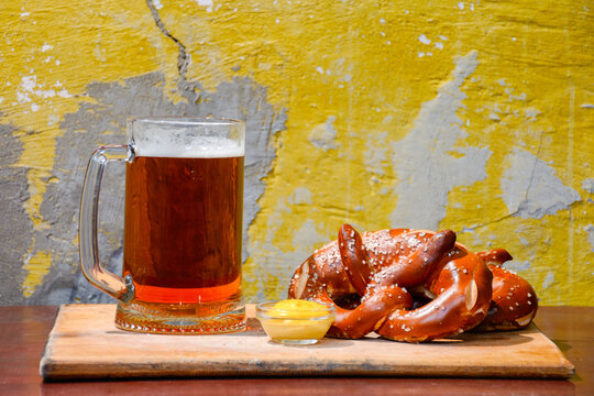 beer pretzel and mustard on a wooden table. rustic oktoberfest drink and food background. grungy wall texture