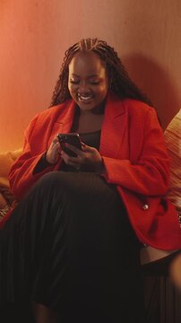 Cheerful African American woman texts on phone, using mobile dating app