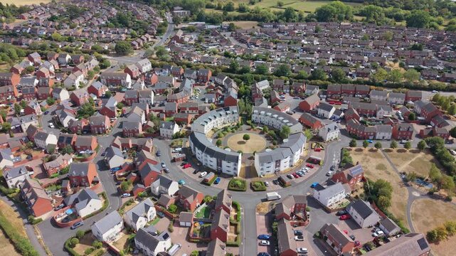 Aerial video of Tewkesbury in Gloucestershire, England, showcasing the historic townscape, residential areas, waterways, green spaces, and surrounding countryside from an elevated perspective